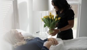 Caregiver bringing flowers to client in bed